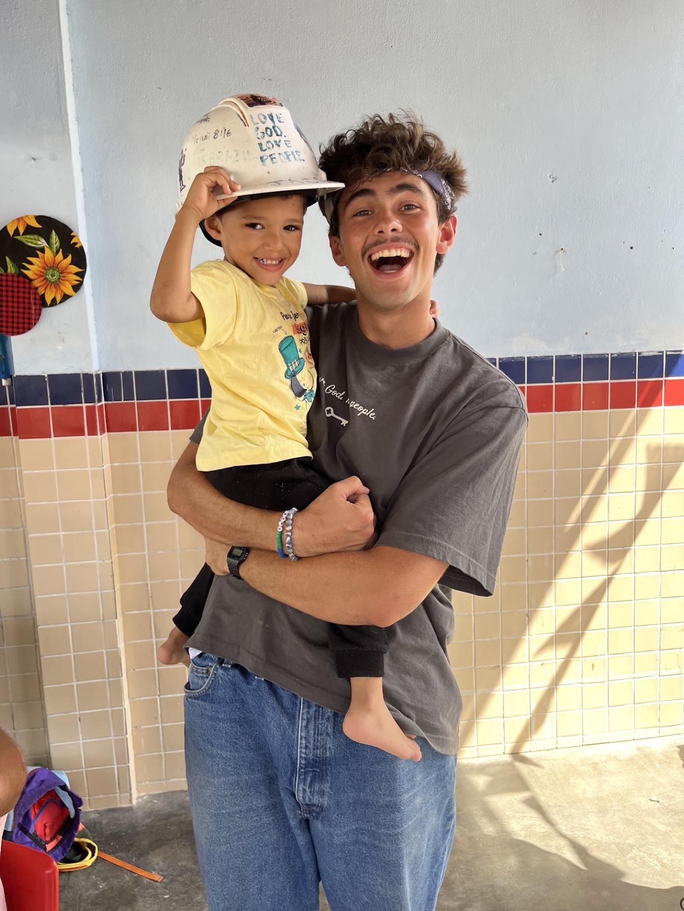 Jacob smiling while holding a child during a humanitarian service trip